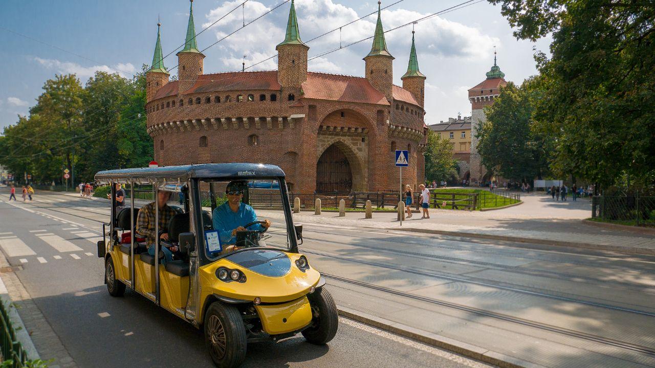 Turyści korzystający z komfortowej i suchej przejażdżki elektrycznym pojazdem, odkrywając zabytki Krakowa"